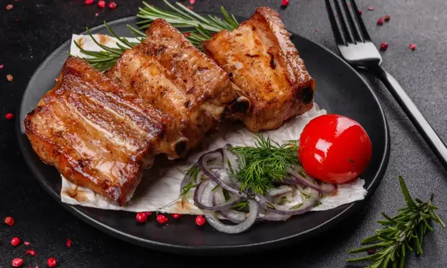 Soczysta żeberka jak piec, podane z pomidorkiem, cebulą i rozmarynem.