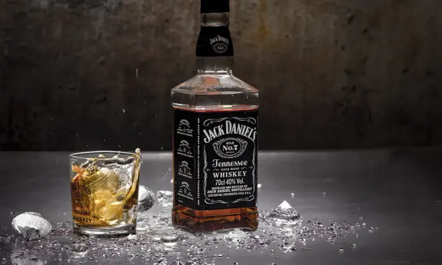 Butelka Jack Daniels i szklanka z whisky, z lodem i błyszczącymi drobinkami. Zastanawiasz się nad Jack Daniels kcal?