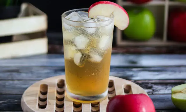 Orzeźwiający drink: whisky z sokiem jabłkowym, lodem i plasterkiem jabłka. Idealny na letnie popołudnie.