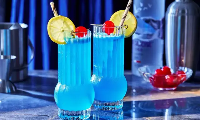 Dwa orzeźwiające drinki Blue Lagoon z cytryną i wiśnią, gotowe do podania.