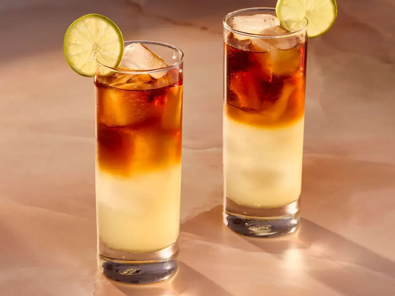 Dwa drinki z lodem i plasterkiem limonki, z ciemnym i burzliwym rumem w środku.