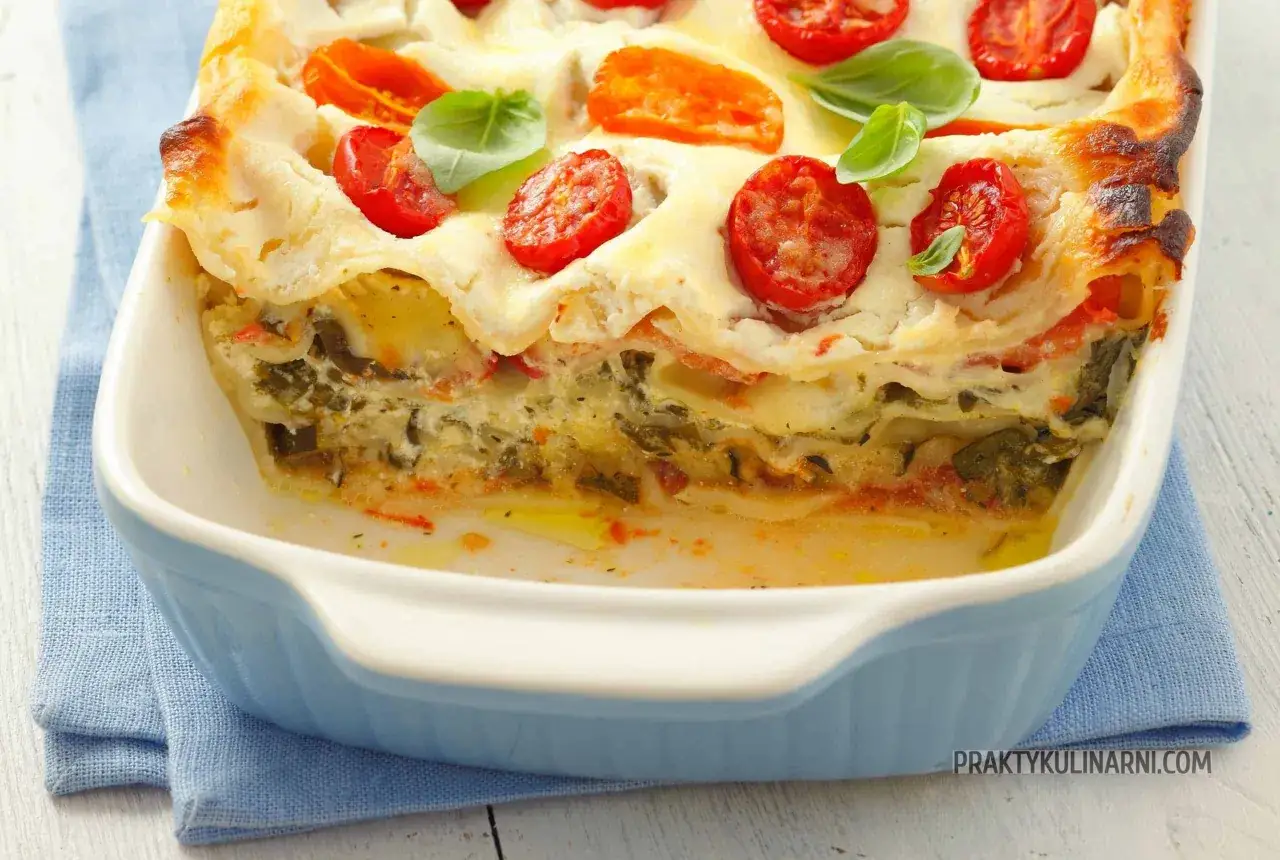 Pyszna lasagne z grzybami, polana sosem beszamelowym i ozdobiona pomidorkami koktajlowymi i bazylią.