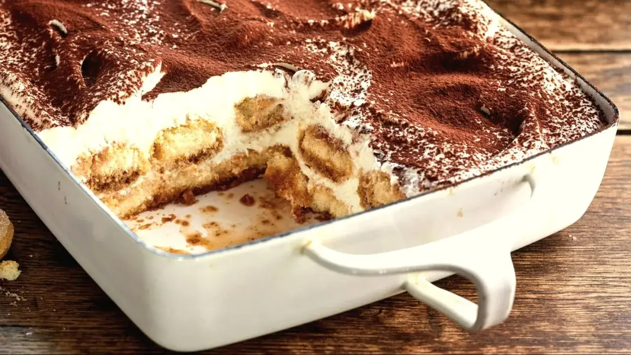 Pyszne tiramisu w naczyniu, z warstwami biszkoptów i kremu, posypane kakao. Zastanawiasz się, jaki alkohol do tiramisu nada mu idealny smak?