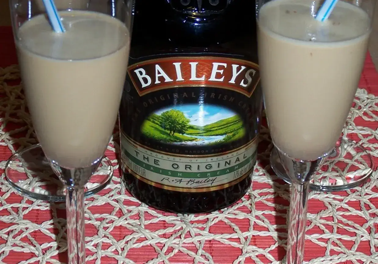 Dwa kieliszki z kremowym, prostym drinkiem z Baileys, obok butelki tego likieru. Idealne na wieczór.