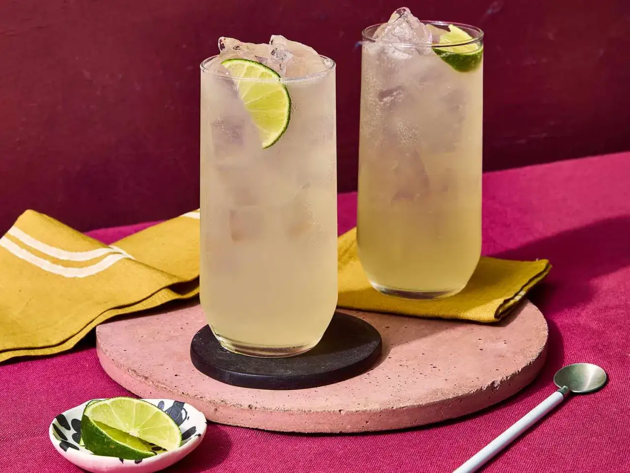 Dwa orzeźwiające drinki Moscow Mule z lodem i limonką, podane na r&oacute;żowej podstawce.