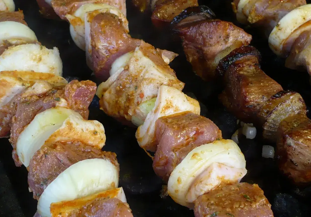 Szaszłyki z polędwiczki wieprzowej z cebulą, przyprawione i grillowane, kuszą apetycznym wyglądem.