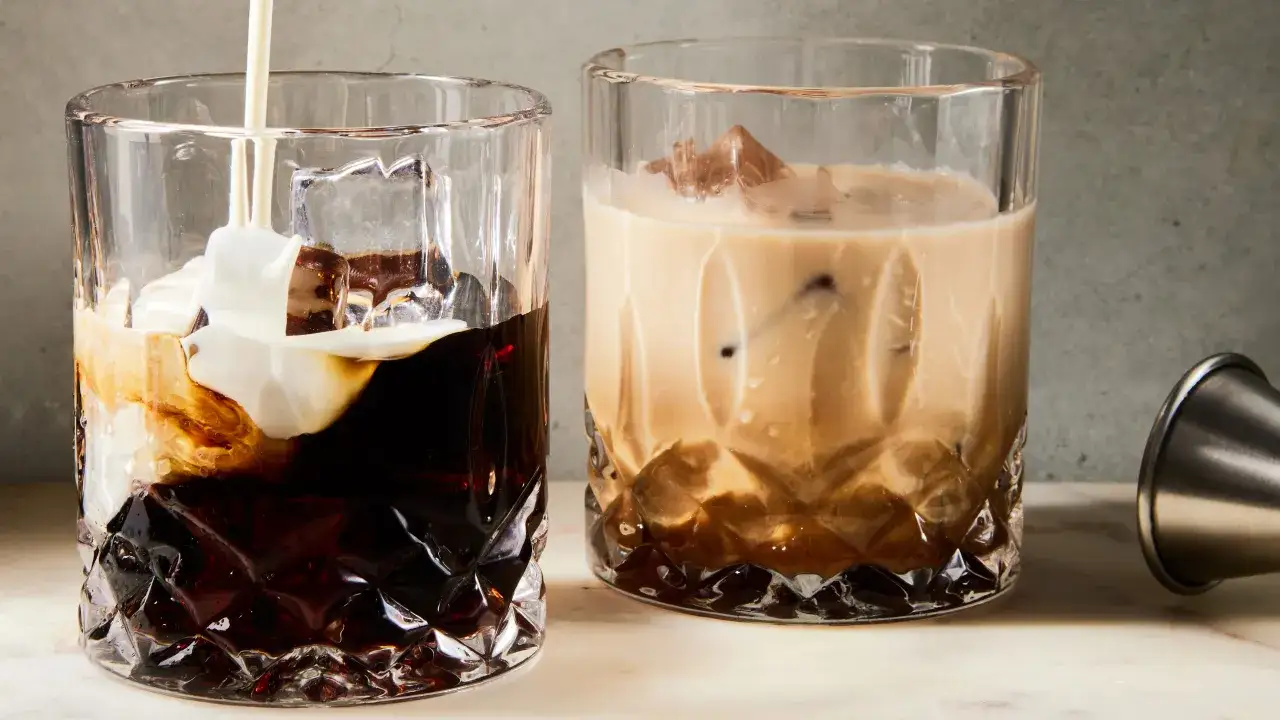 Dwa drinki white russian z lodem. Na pierwszym widać, jak wlewana jest śmietanka do ciemnego likieru.
