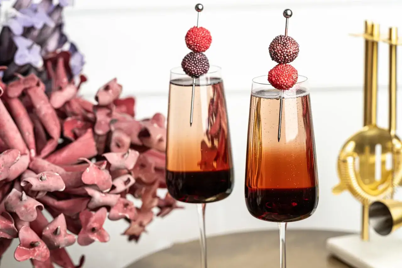Dwa eleganckie drinki z winem musującym, ozdobione koralikami, gotowe na toast.