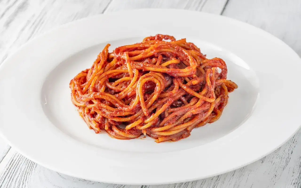 Spaghetti all'assassina, pikantne, czerwone danie z makaronem, podane na białym talerzu.