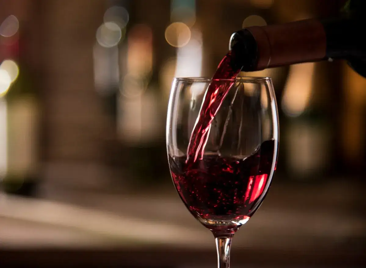 Czerwone wino nalewane do kieliszka, tworząc idealną lampkę wina wieczorem.