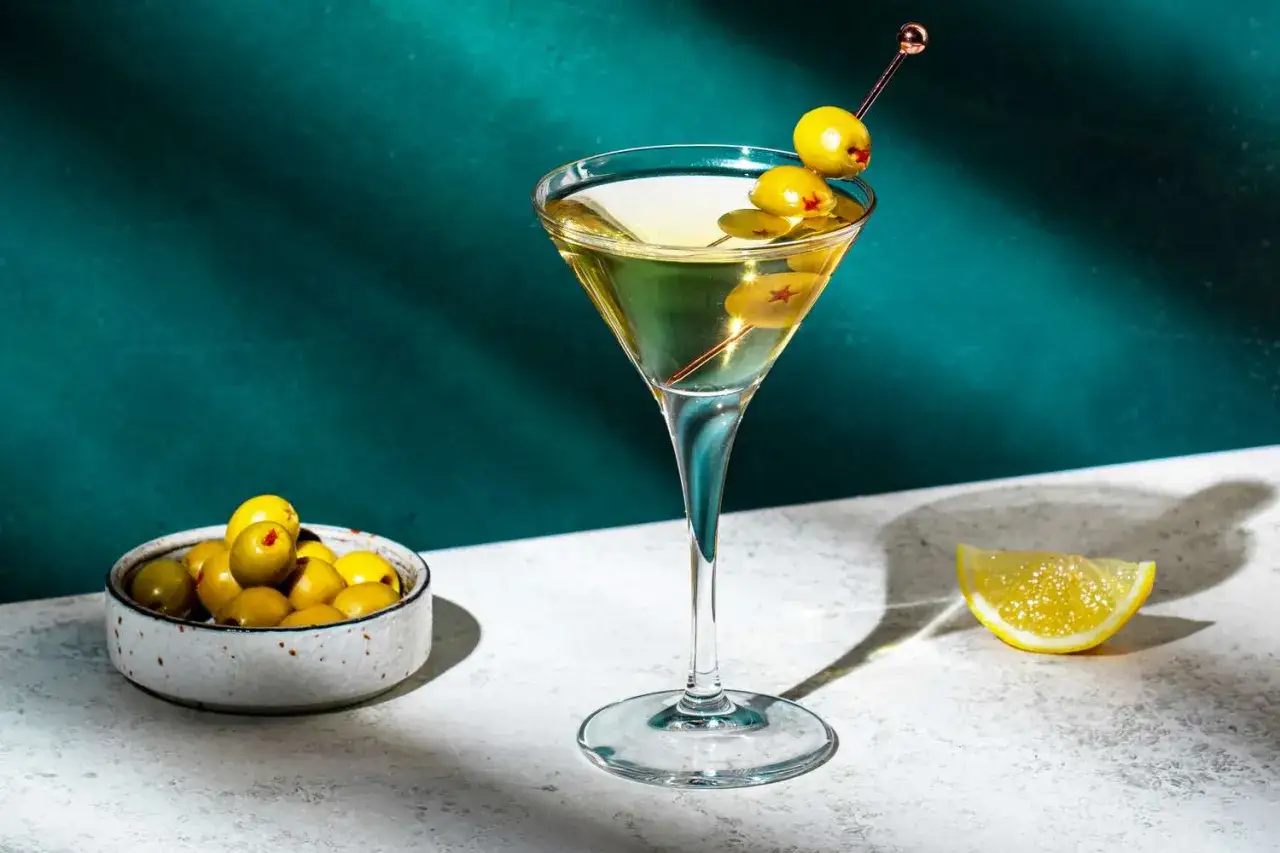 Elegancki martini drink z oliwkami i plasterkiem cytryny, gotowy do degustacji.