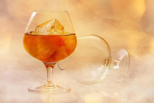Szklanka z bursztynowym brandy i lodem, obok pusta, przewrócona kieliszek. To jest brandy, co to za napój?