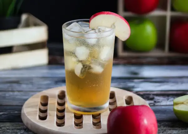 Orzeźwiający drink: whisky z sokiem jabłkowym, lodem i plasterkiem jabłka. Idealny na letnie popołudnie.